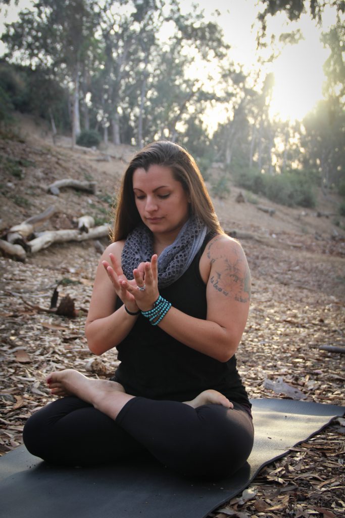 Peace Love And Yoga, a hot yoga studio in Carlsbad California shares 7 reasons why you should add yoga to your resolutions; woman sitting in lotus with hand mudras.